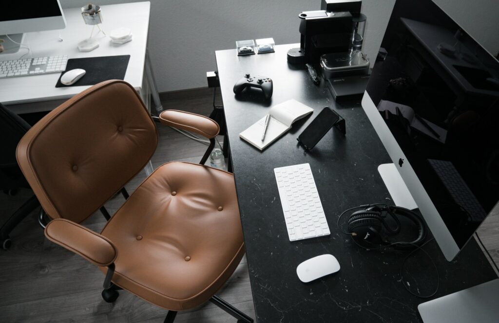 Modern ergonomic office chair positioned beside a wooden desk in a bright, minimalist workspace.