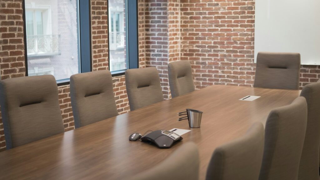 Modern conference tables arranged in a well-lit meeting room with a wood finish